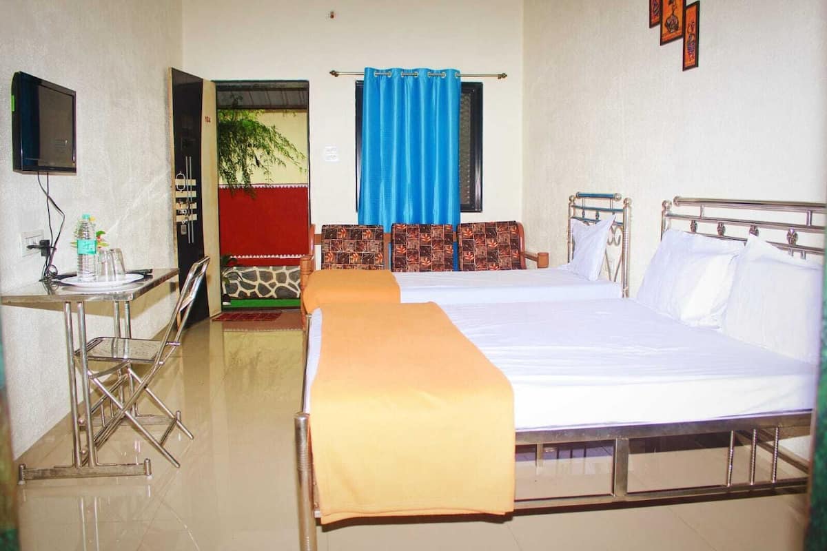A hotel room with a bed, a desk with a chair, a television, and a window with curtains.