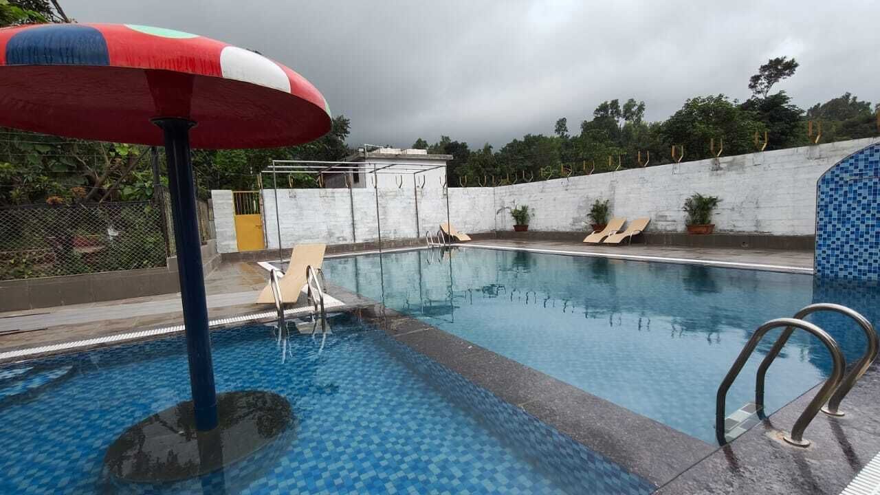 Piscina com borda azulejada, escada de metal e cadeiras de sol.