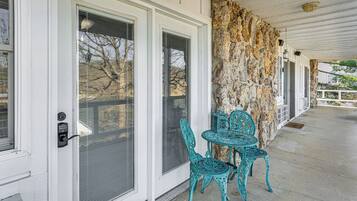 A covered porch with a stone wall, a door with a security keypad, and turquoise metal chairs.
