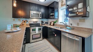 Una cucina moderna con mobili scuri, elettrodomestici in acciaio inossidabile e un piano di lavoro in granito.