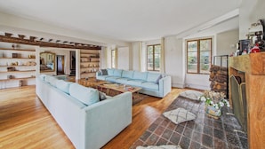Ein geräumiges Wohnzimmer mit einem hellblauen Sofa, Holzdielen und einem Kamin.