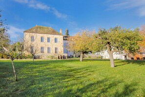 A stone building with a grassy lawn and trees.