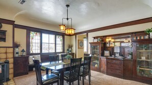 Une salle à manger avec une table et des chaises en bois, un lustre et une fenêtre à vitraux.