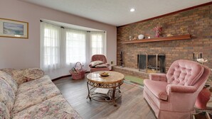 Una sala de estar con sofá, sillón, una mesa redonda y chimenea.