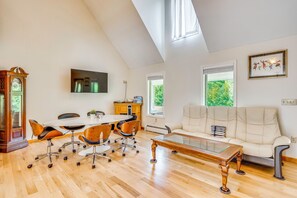 A spacious living area with a high ceiling, a large window, a white sofa, a dining table with chairs, and a wooden coffee table. - Explore the White Mountains! Spacious Rural Home (Thornton)