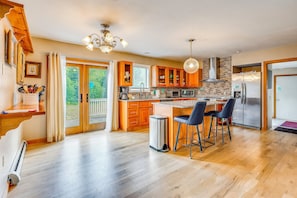 Una cocina moderna con armarios de madera, un refrigerador de acero inoxidable y una isla grande con taburetes de bar.
