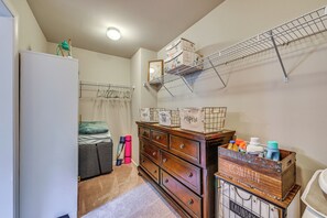 A bedroom with a bed, a dresser, a drying rack, and a wardrobe.