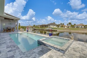 A swimming pool with a hot tub, a patio area, and a view of neighboring houses. - Luxe Canal-Front Getaway w/ Pool in Punta Gorda! (Punta Gorda)