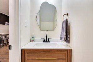 A bathroom with a white sink, wooden cabinet, and a mirror.