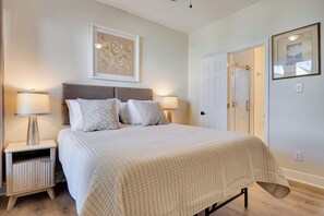 A bedroom with a large bed, two bedside tables with lamps, a headboard, and two framed artworks on the walls.