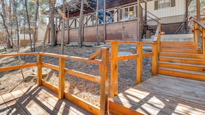 A wooden deck with a railing, a staircase leading to a building, and a forested area. - Near Grindstone Lake & Family Fun! Cozy Cabin (Ruidoso)
