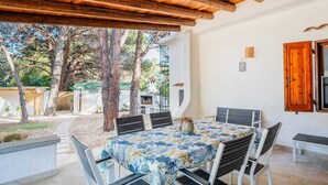 Eine Terrasse im Freien mit einem runden Tisch, vier Stühlen und einer Holzbeschattung.