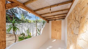 Ein Zimmer mit Steinwand, Holzbalken und Blick auf einen Garten.