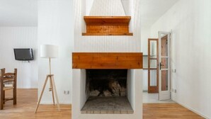 Ein Zimmer mit Kamin, einem an der Wand montierten Fernseher und Holzboden.
