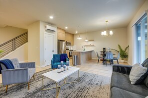 A modern living room with a sofa, a coffee table, and a dining area with chairs and a table.