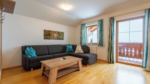 Ein Wohnzimmer mit einer Couch, einem Couchtisch, einem Bild an der Wand und einer Glastür mit Vorhängen.