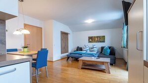 Ein modernes Wohnzimmer mit einer Couch, einem Couchtisch und einem Essbereich mit Stühlen und einem Tisch.