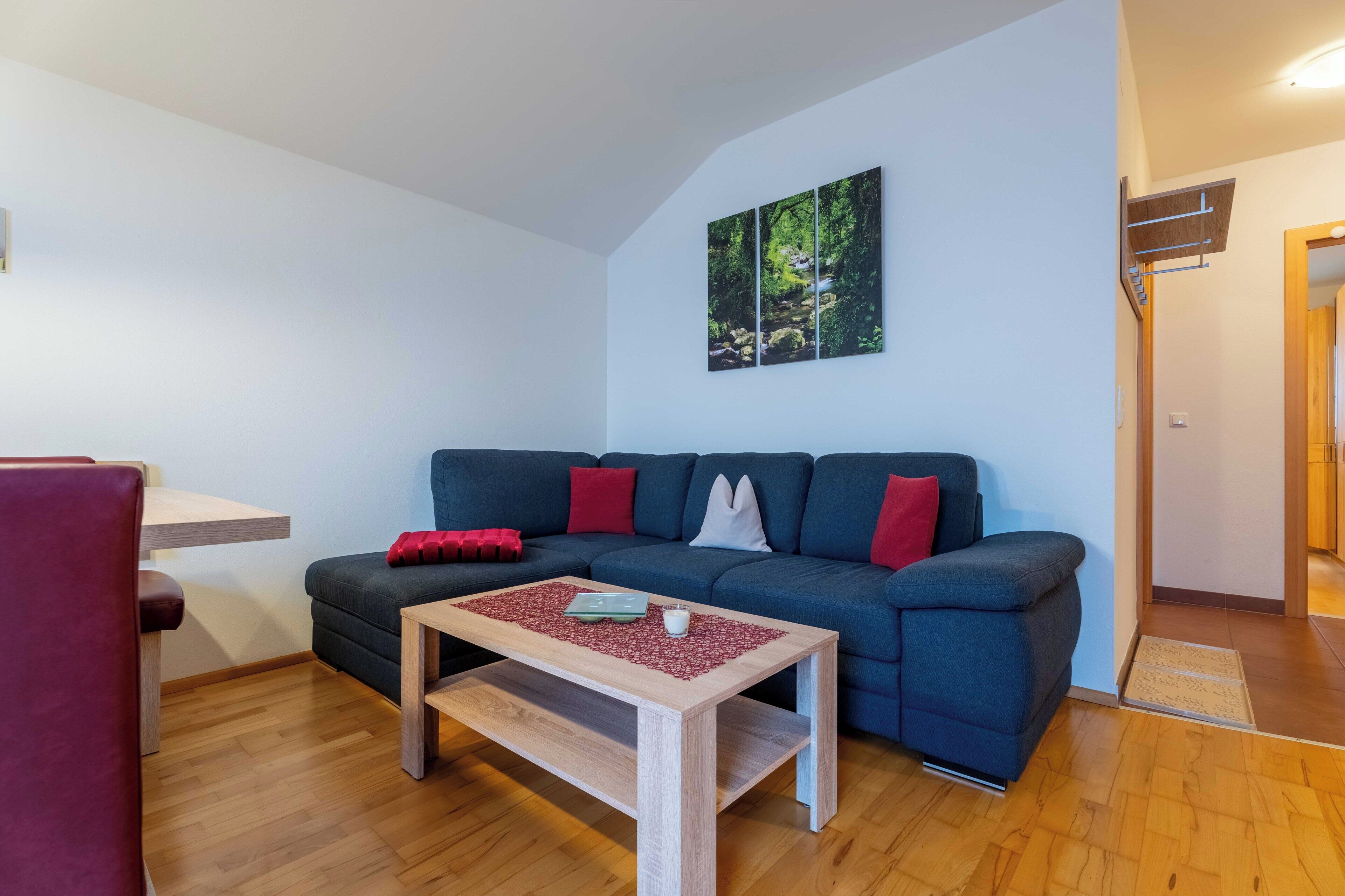 A living room with a sofa, a coffee table, and a painting on the wall.
