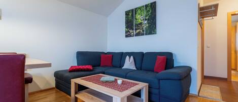 A living room with a sofa, a coffee table, and a painting on the wall.
