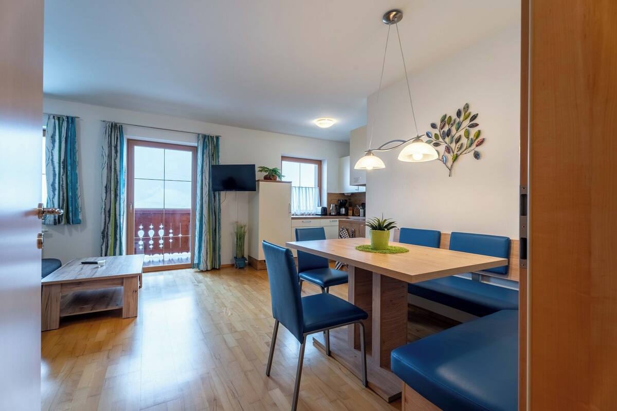 Una sala moderna con una mesa de comedor de madera, sillas azules y un sofá.