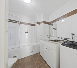 Ein Badezimmer mit Badewanne, Waschbecken, Spiegel und Waschmaschine.