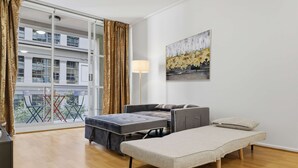 Quarto com sofá, mesinha, luminária de chão e um quadro na parede.