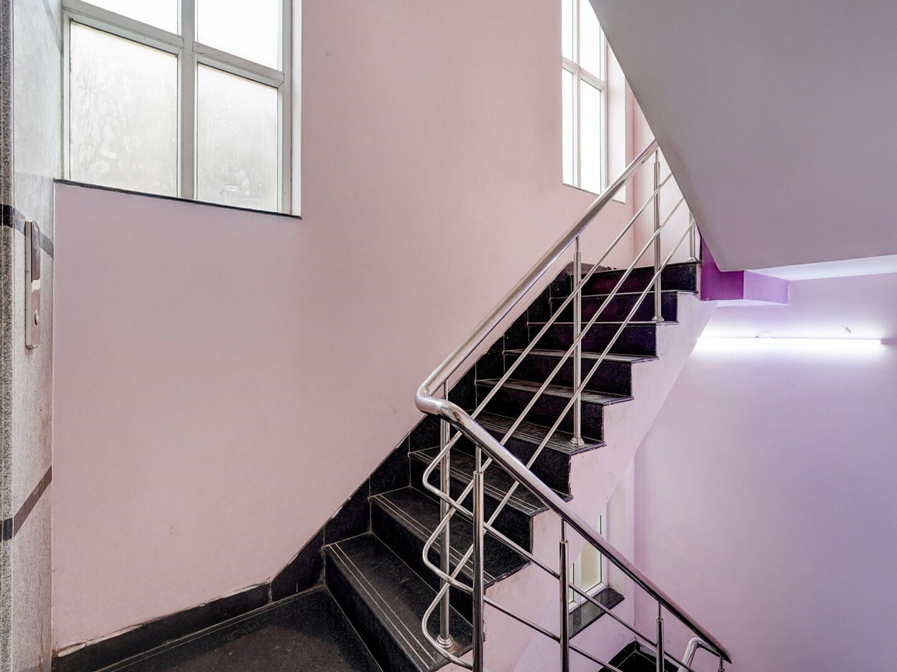 A staircase with metal railings and a handrail, leading to a landing with a window.