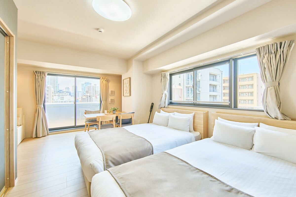 Quarto de hotel com duas camas, uma escrivaninha e vista para a cidade.