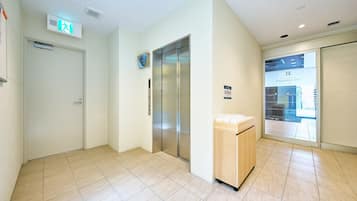 A hotel lobby with an elevator, a reception desk, and a glass door leading to a spa area.