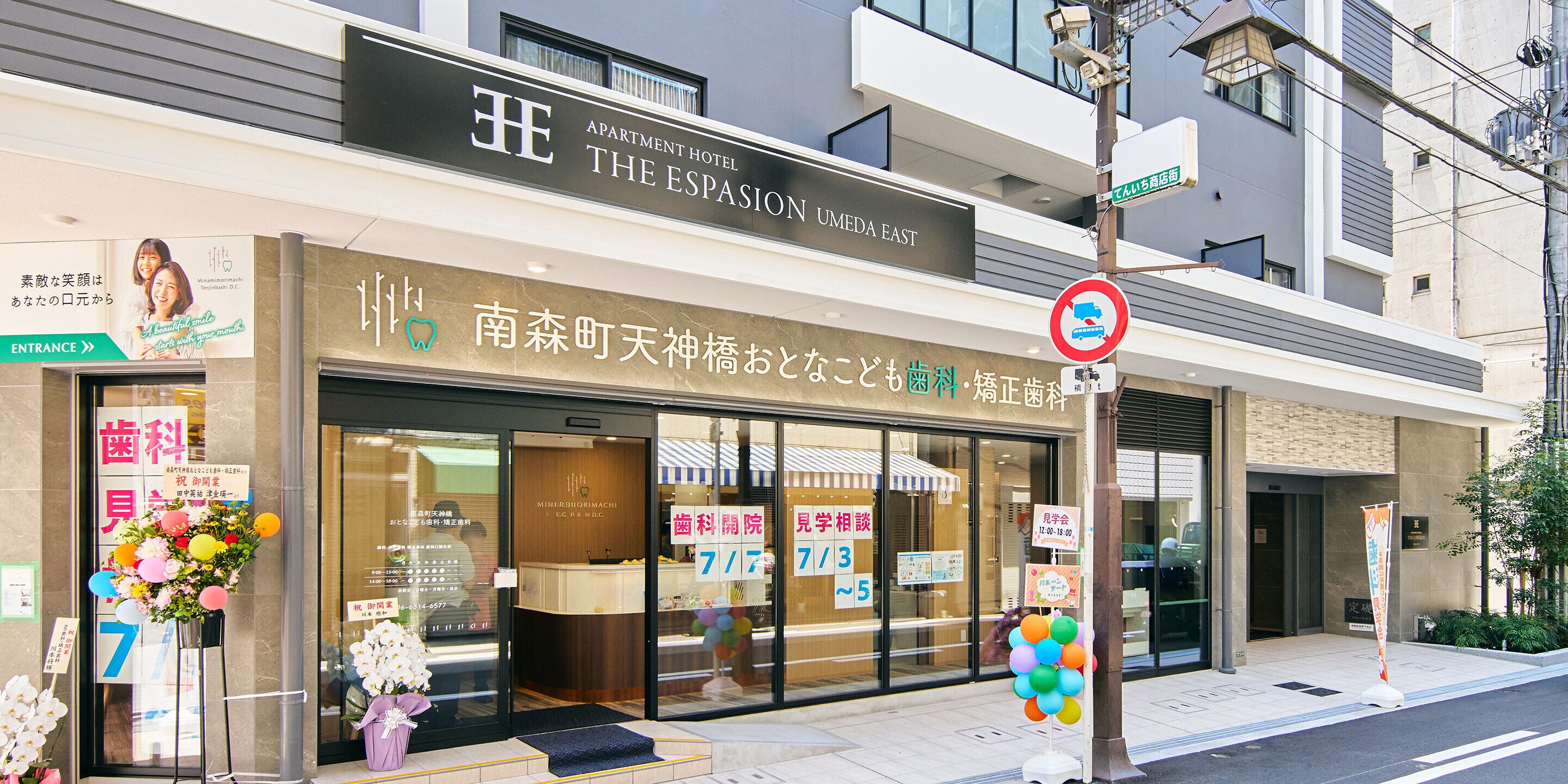 A building with a sign for 'The Espasion N Umeda East' and a no-parking sign.