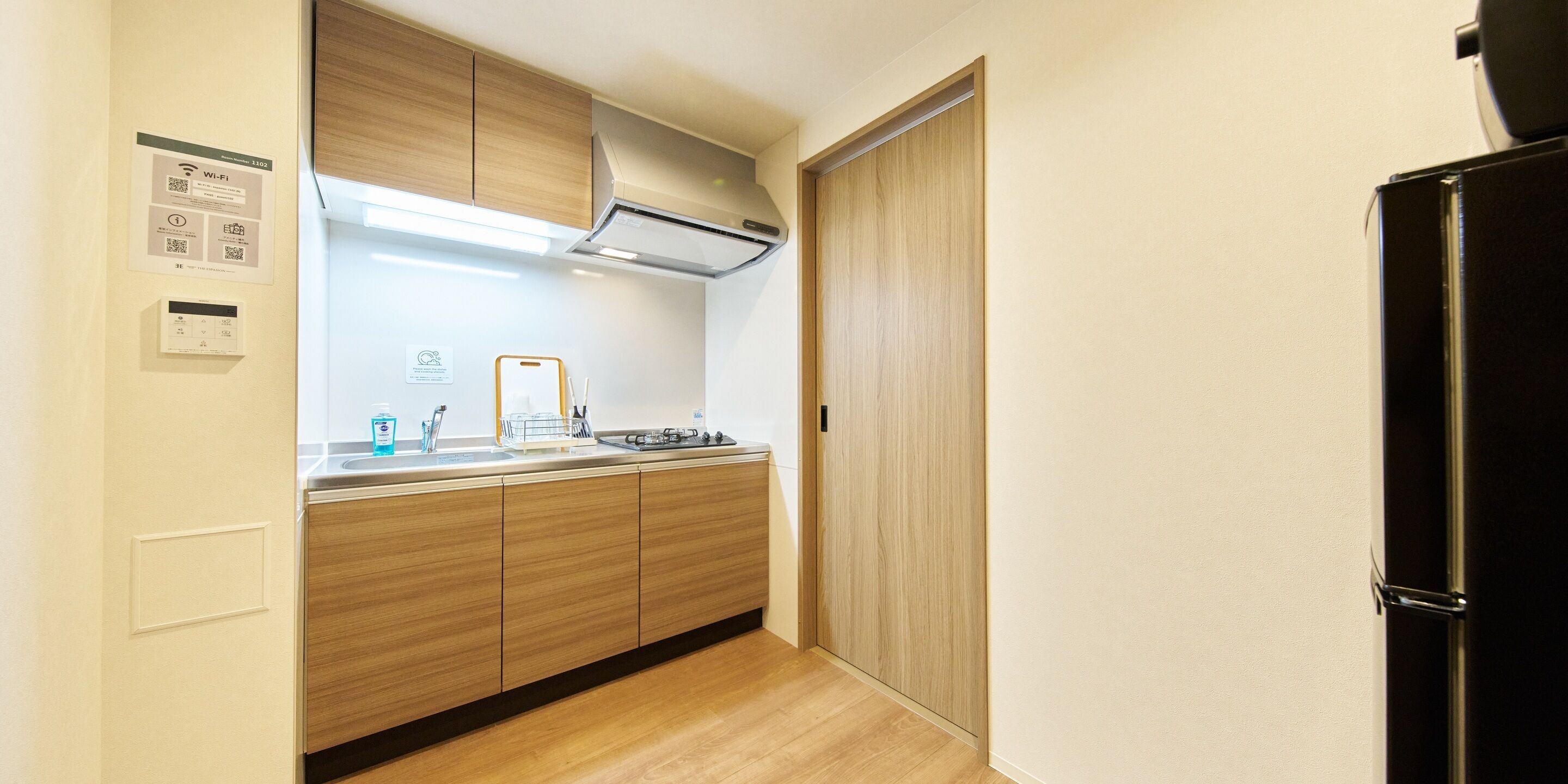 A compact kitchen with wooden cabinets, a built-in stove, and a black refrigerator.