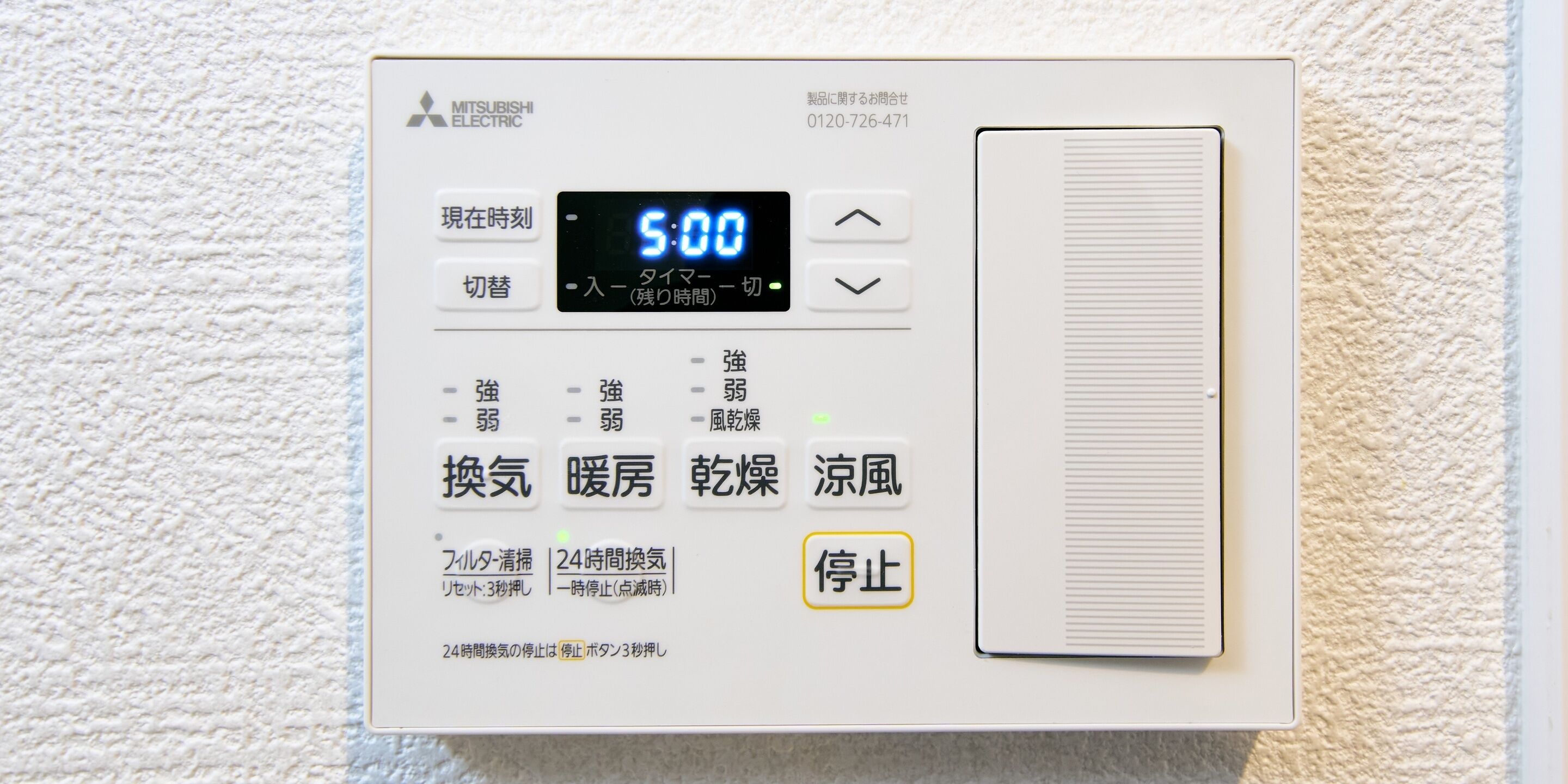 A Mitsubishi Electric air conditioner unit with a digital display, control buttons, and a vent.