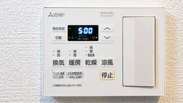 A Mitsubishi Electric air conditioner unit with a digital display, control buttons, and a vent.