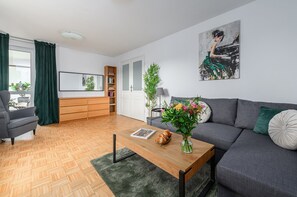 A modern living room with a sofa, a coffee table, a bookshelf, and a painting on the wall. - Cozy Apartment with balcony near Museum (Warsaw)