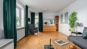 Un salon moderne comprenant un canapé, une table basse, un fauteuil, une bibliothèque et un radiateur.
