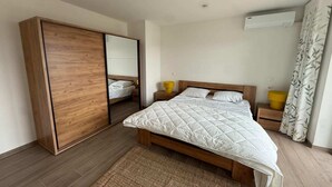 A bedroom with a bed, a wardrobe, a bedside table, an air conditioning unit, and a curtain. - Modern apartment Hasselt 2p (Hasselt)