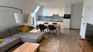 A modern living room with a sofa, coffee table, and dining area with chairs. - Modern apartment Hasselt 2p (Hasselt)