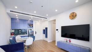 Uma sala de estar moderna com um sofá azul, uma mesa de centro redonda e uma televisão de tela plana na parede.