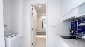 Uma cozinha moderna com armários brancos, painel azul e bancada com chaleira e cafeteira.