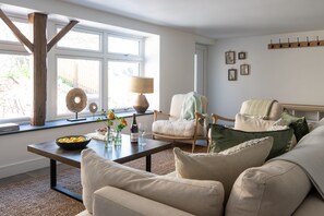 Un salon comprenant un canapé, une table basse, un fauteuil et une fenêtre donnant sur l’extérieur.