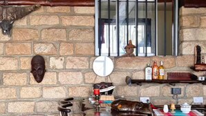 A rustic interior with stone walls, wooden furniture, and a stone floor.