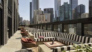 Terraza en la azotea con mobiliario exterior, vista al horizonte de la ciudad y arquitectura moderna.
