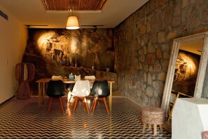 Un comedor con pared de piedra, una mesa de madera y sillas negras.