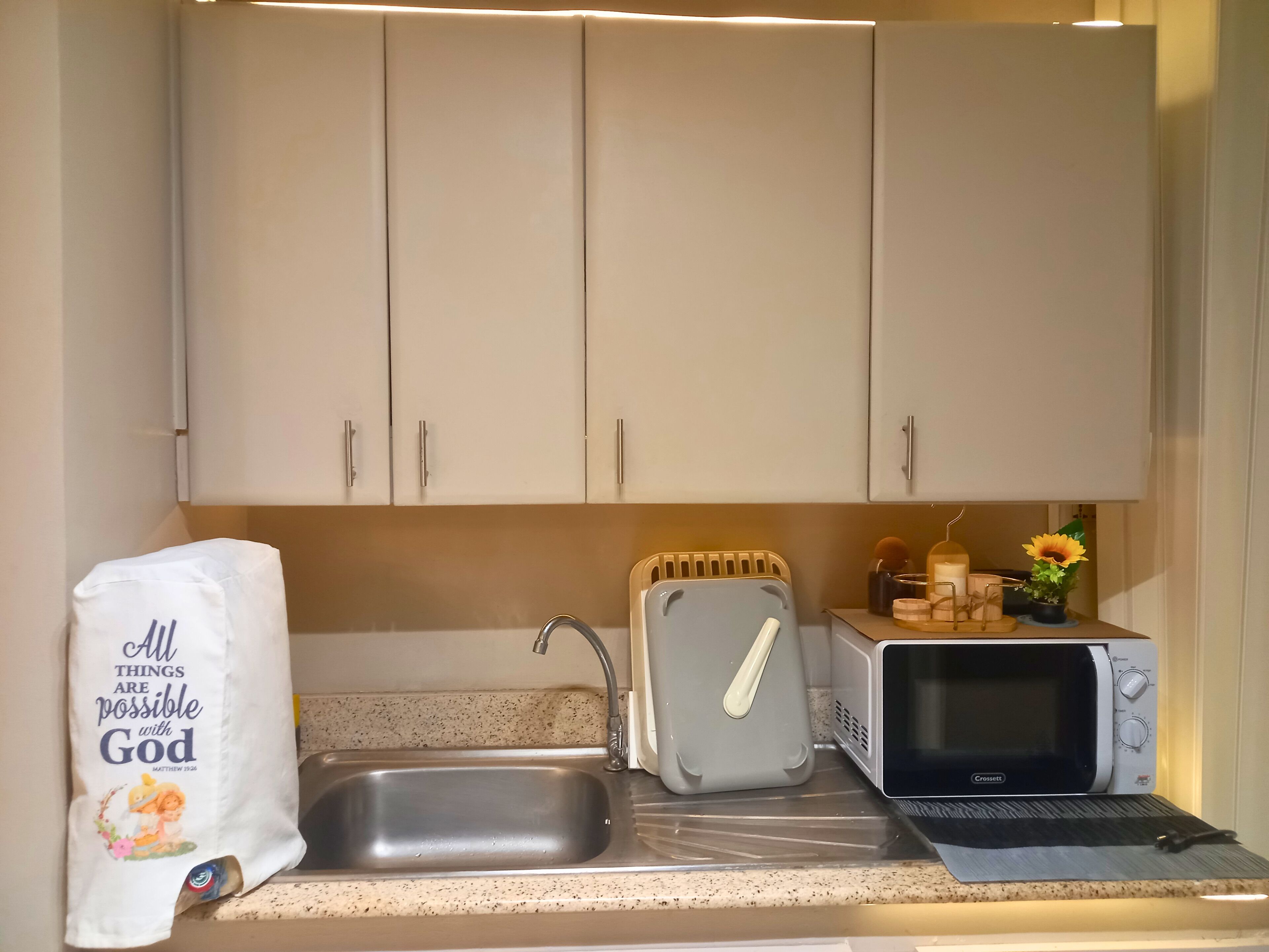 Une cuisine équipée d’un évier, d’un grille-pain, d’un four à micro-ondes et d’un sac de provisions.