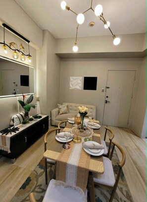 Un'area pranzo con tavolo rotondo, sedie, lampadario, divano e una porta.
