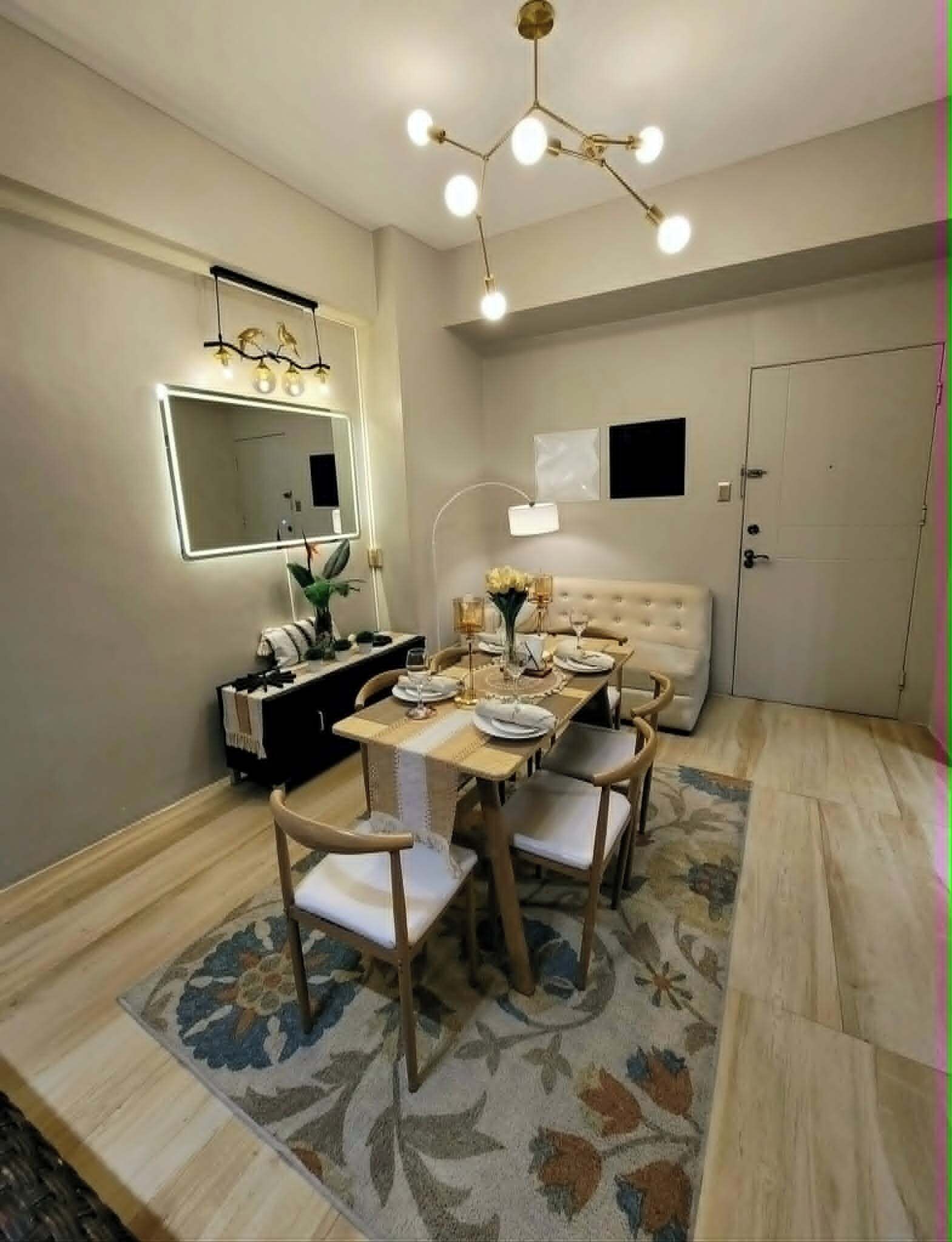 Un coin repas avec une table dressée pour quatre personnes, un canapé, un miroir et un luminaire au plafond.