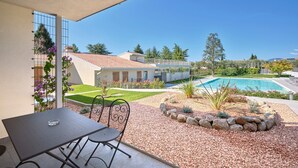 Eine Terrasse mit Tisch und Stühlen, ein Schwimmbad und ein Garten mit Steingrenze.