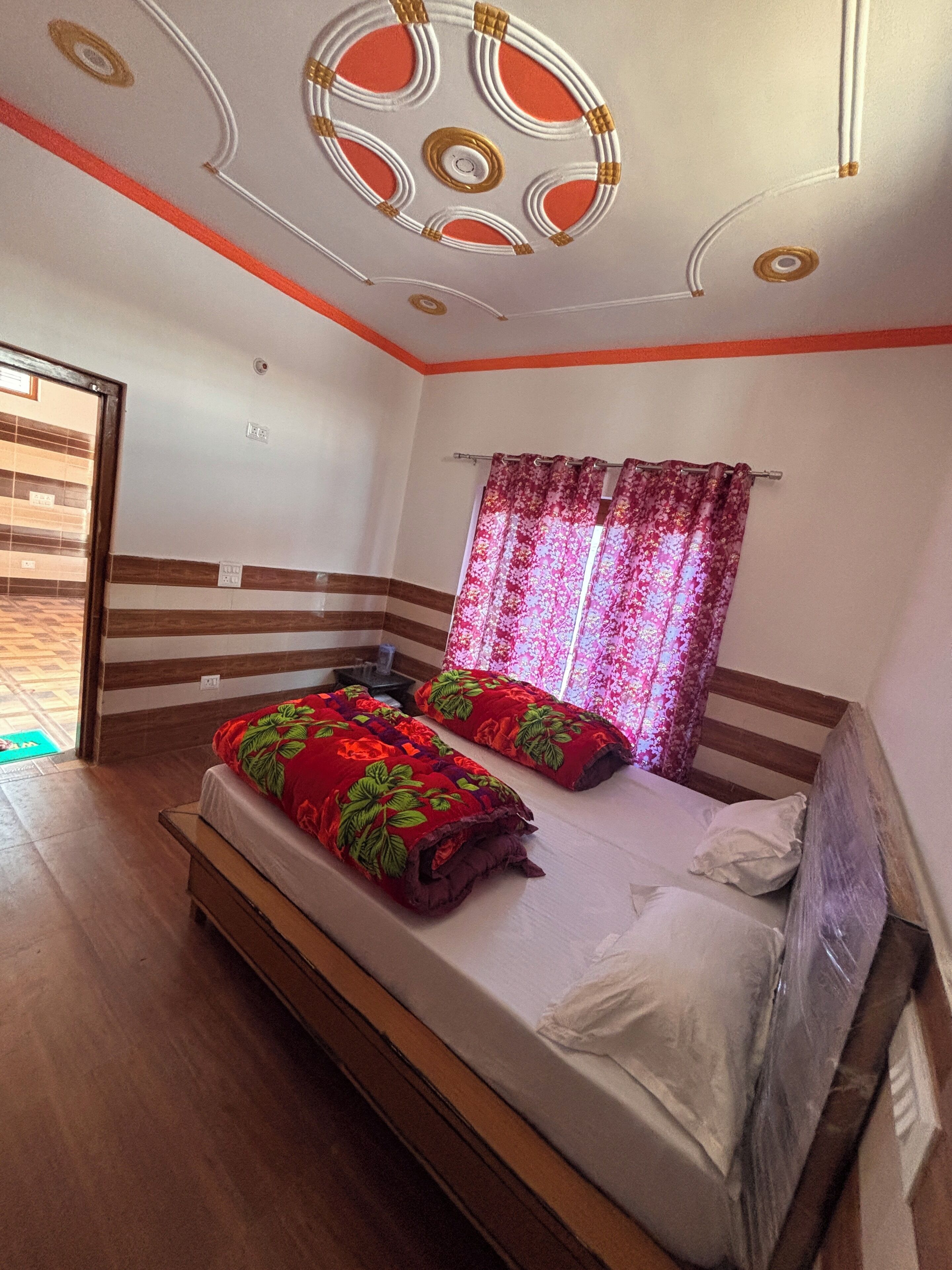 A bedroom with a bed, curtains, and a ceiling design.