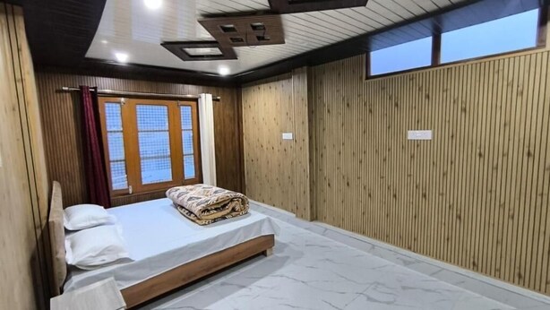 A bedroom with a bed, wooden walls, a window, and a ceiling with recessed lighting. - Omji Temple View Kharsali (Rajgarhi)