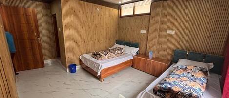 Una habitación con dos camas, paredes de paneles de madera, ventilador de techo y suelo de baldosas.